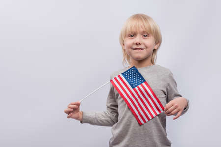 Young boy holding an American flag on white background. Study of American English.の写真素材