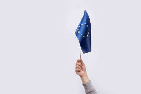 Flag of the European Union in childs hand on white background
