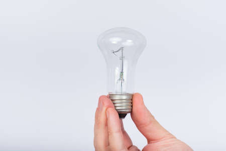 Incandescent bulb in male hand on white background. Close upの写真素材