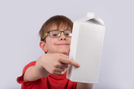 Happy boy gives package of milk or juice. Copy space. Template. Mockup.の写真素材