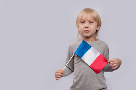 Fair-haired boy holding flag of France. Training in France. Learning French for children.の写真素材
