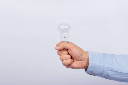 Incandescent bulb in male hand on white background. Side view.