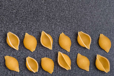 Conchilioni on gray background. Italian pasta. Close up. Cook background. Copy space. Template. Mockup.の写真素材