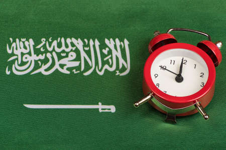 Saudi Arabia flag and vintage alarm clock close up. Green flag with sword.の写真素材
