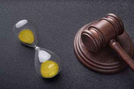 Hourglass and judges gavel on black background. Time of auction. Law and time concept.の写真素材