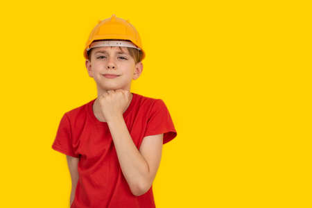 Teen boy in hard hat on yellow background. Choice of profession. Copy space.