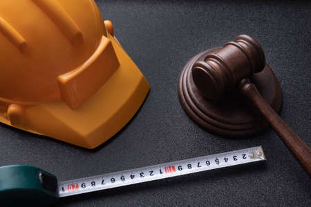 Wooden judge gavel, yellow building helmet and tape. Construction law concept. labor-related legal...