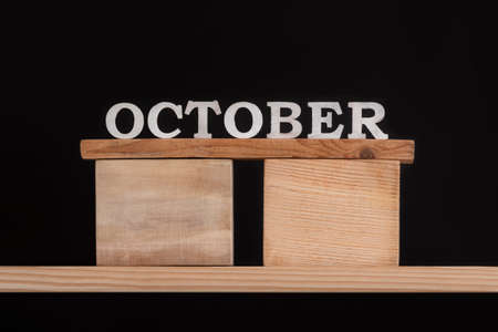 Word October by wooden letters on black background. Front view. Autumn calendar. Fall month.の写真素材