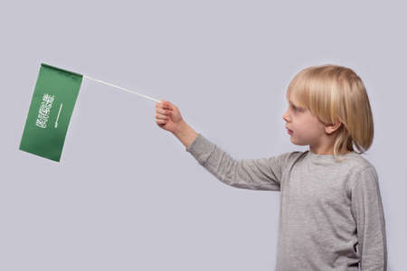 Fair-haired boy holding flag of Saudi Arabia on white backgroundの写真素材