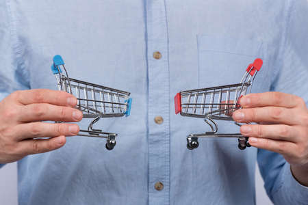 Male hands holding two toy grocery cart. Shopping concept.