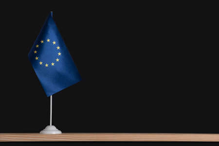 Flag pole, national table flag of EU on black background. Copy space.