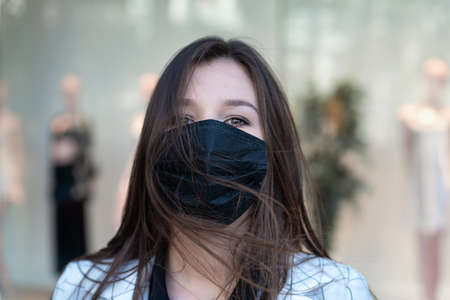 Portrait of young woman in black protective medical maskの写真素材