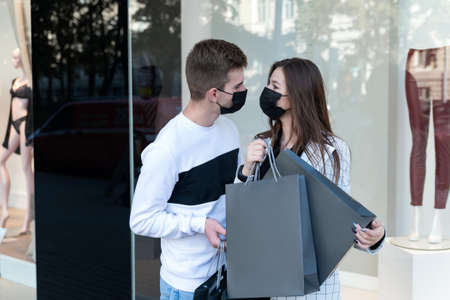 Love couple in medical masks after shopping with packages in hands. Black friday and quarantine.