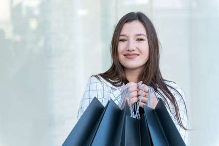 Portrait of young woman with black shopping bag. Close up.