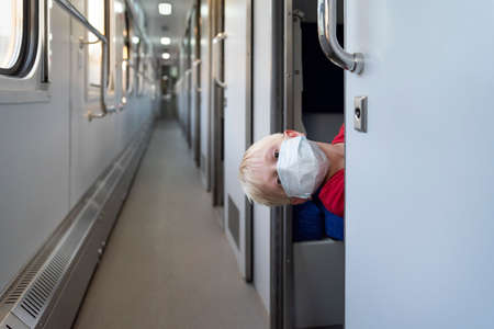 Child traveling by train during the COVID pandemic. Boy in protective mask.