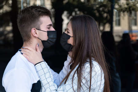 Man and woman kissing each other in black protective medical mask on face. Quarantine pandemic...
