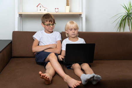 Two boys watching studying video on laptop. Children with laptops in hands.