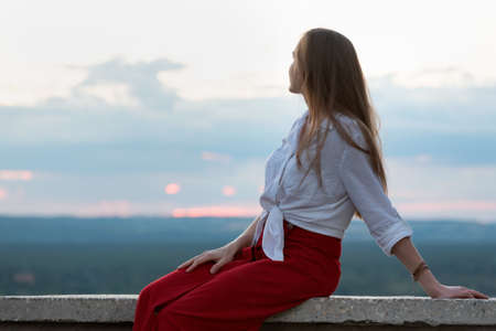 Portrait of young woman against sky background. Girl thinks and looks into the distance.の写真素材
