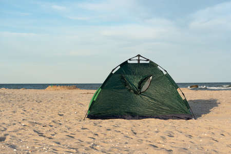 Green tent on sandy seashore. Camping at sea with tent. Travel.の写真素材