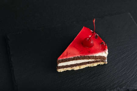 Piece of red fruit cake on black plate. Top view of cake on black background.の写真素材