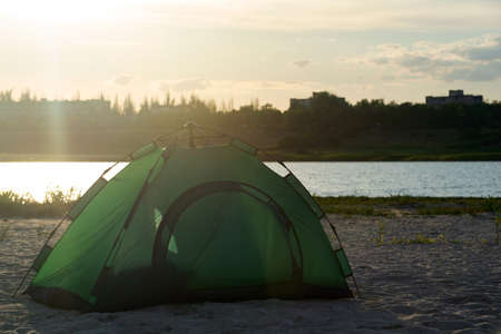 Tourist tent on sandy bank against river background. Camping.の写真素材