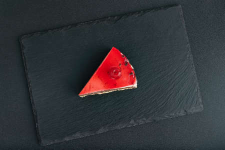 Top view on piece of red fruit cake on black stone trayの写真素材