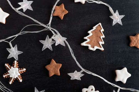 Christmas cookies stars, fir tree and Garland on black background. Gingerbreads.