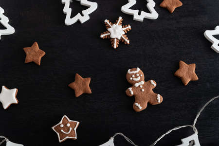 Christmas gingerbread man and stars on black background. Holiday baking.
