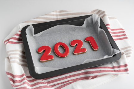 Set of red numbers 2021, ginger cookies on baking sheet. Traditional Christmas gingerbread.