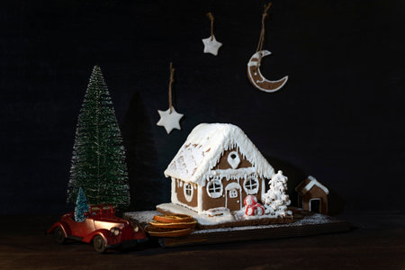 Gingerbread house and cookies next to toy car and small Christmas tree. Merry Christmas and Happy...