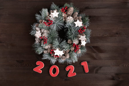 Christmas wreath and Inscription 2021 gingerbread cookie on wooden background.
