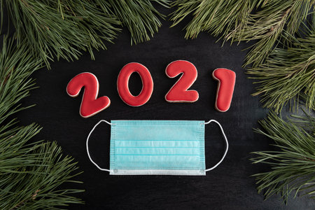 Lettering 2021 and medical mask. Fir tree on black background. Extension of COVID quarantine in 2021.の写真素材