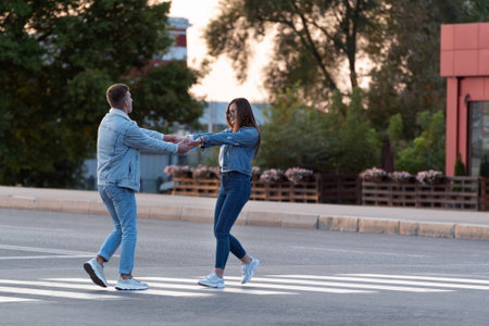 Couple in love is dancing on pedestrian crossing, holding handsの写真素材