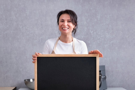 Portrait of laughing woman with chalk board in her hands. Copy space, mock upの写真素材