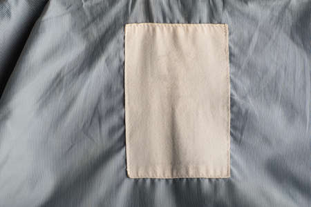 White textile tag on gray fabric. Empty space.