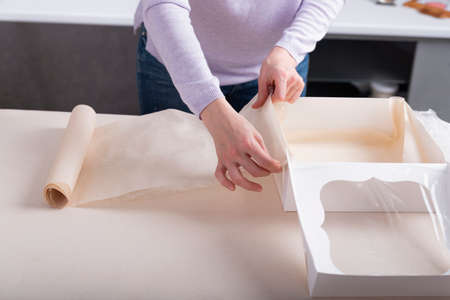 Gift wrapping process in white cardboard box. Confectioner packs sweets.