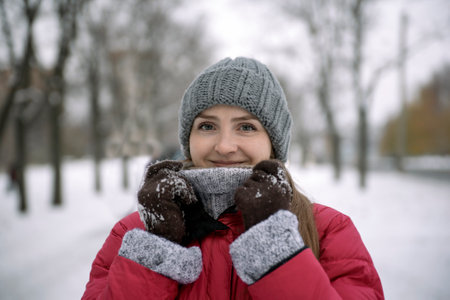 Portrait of happy young woman in warm hat against background of winter parkの写真素材