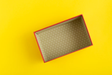 Open empty cardboard box on yellow background. Top view.
