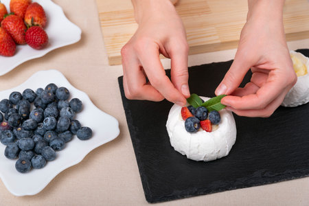 Womens hands decorate cake. Fresh berries and cake top viewの写真素材