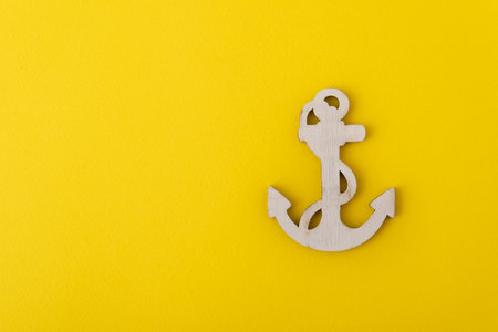 Wooden anchor on yellow background. Concept of sea cruises. Marine theme.の写真素材