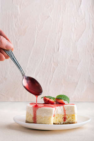 Double layer cheesecake with fresh strawberries and berry syrup. Vertical frame.