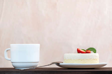 Slice of cake and cup of coffee side view. Piece of cheesecake garnished with strawberriesの写真素材