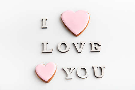 I LOVE YOU lettering on white background next to pink gingerbread cookies with icingの写真素材