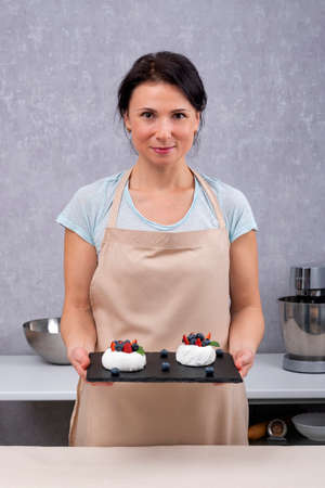 Portrait of woman pastry chef with cakes in her hands. Cakes Anna Pavlova.の写真素材