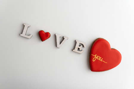 Inscription Love on white background with heart instead of letter O. Big gingerbread red heart