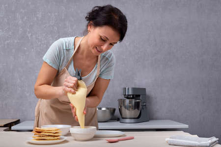 Women pastry chef prepares cake from shortcakes and cream. Process of making cakeの写真素材