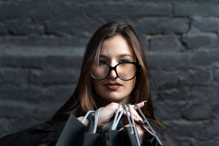 Close up portrait of young brunette woman in glasses on black brick wall background