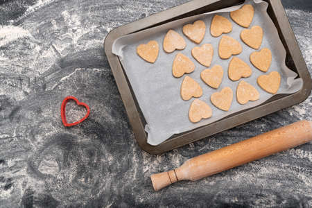 Wooden rolling pin and baking sheet with heart-shaped cookies. Homemade baking.の写真素材