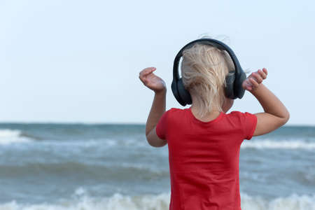 Boy with headphones looks at the sea and listens to music. Back viewの写真素材