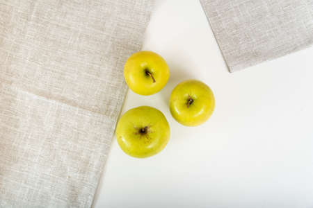 Three green apples are on table next to textile napkins. Top view.の写真素材